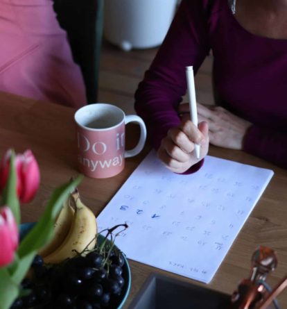 Woman sat at a table writing a Sustainability Action Plan.