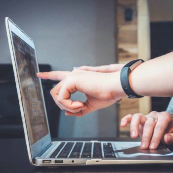 Hands pointing at a laptop screen