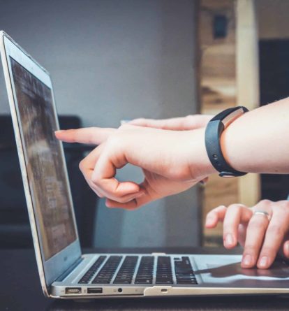 Hands pointing at a laptop screen