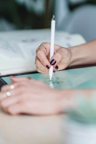 Womans's hands illustrating on a tablet using a pencil.