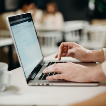Hands typing on a laptop at a desk.
