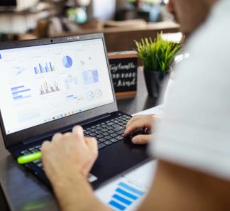 Man working on a laptop showing data visualizations as graphs.