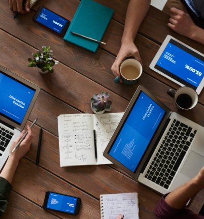 Top view of professional at a a table discussing meeting notes on laptops.